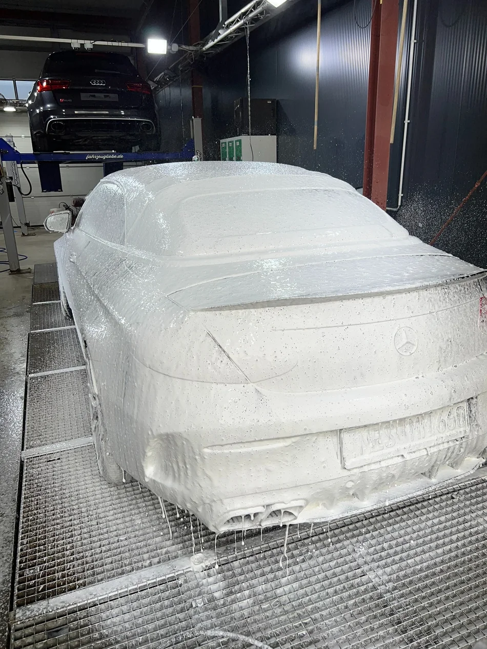Heck eines Mercedes-Cabrios unter einer geschlossenen Schaumschicht auf dem Waschplatz.
